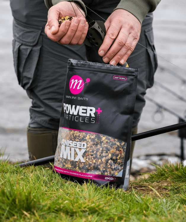 Mix Semilla Mainline Power+ Ani-Seed 2 kg for carpfishing, showing packaging and hands preparing tackle.