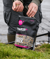 Mix Semilla Mainline Power+ Ani-Seed 2 kg for carpfishing, showing packaging and hands preparing tackle.